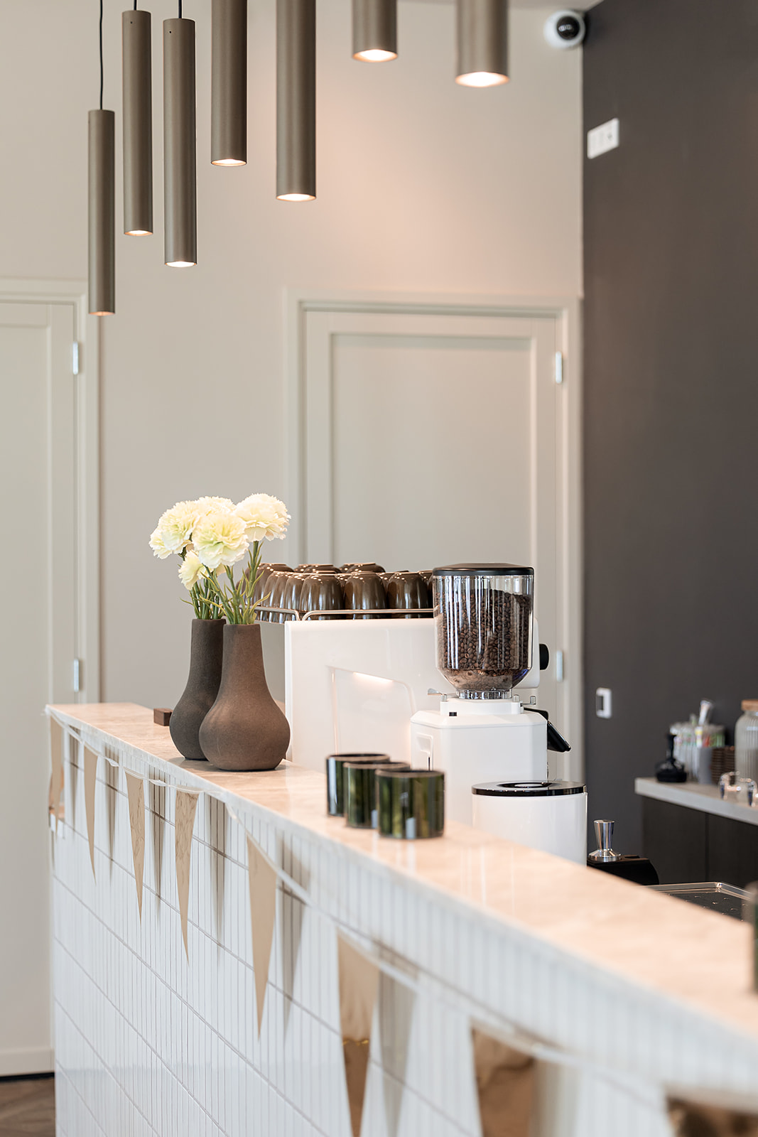 De bar van Bij Herbert met koffiezetapparaat, verse bloemen en bronzen pendellamp