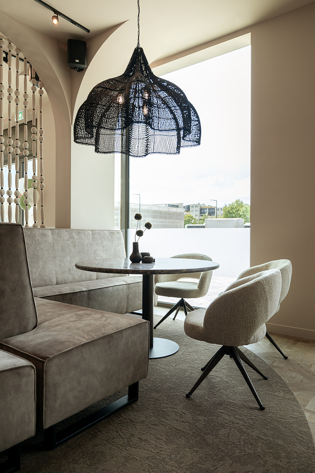 Luxe zithoek van brasserie Bij Herbert met gevlochten hanglamp en zicht op het station